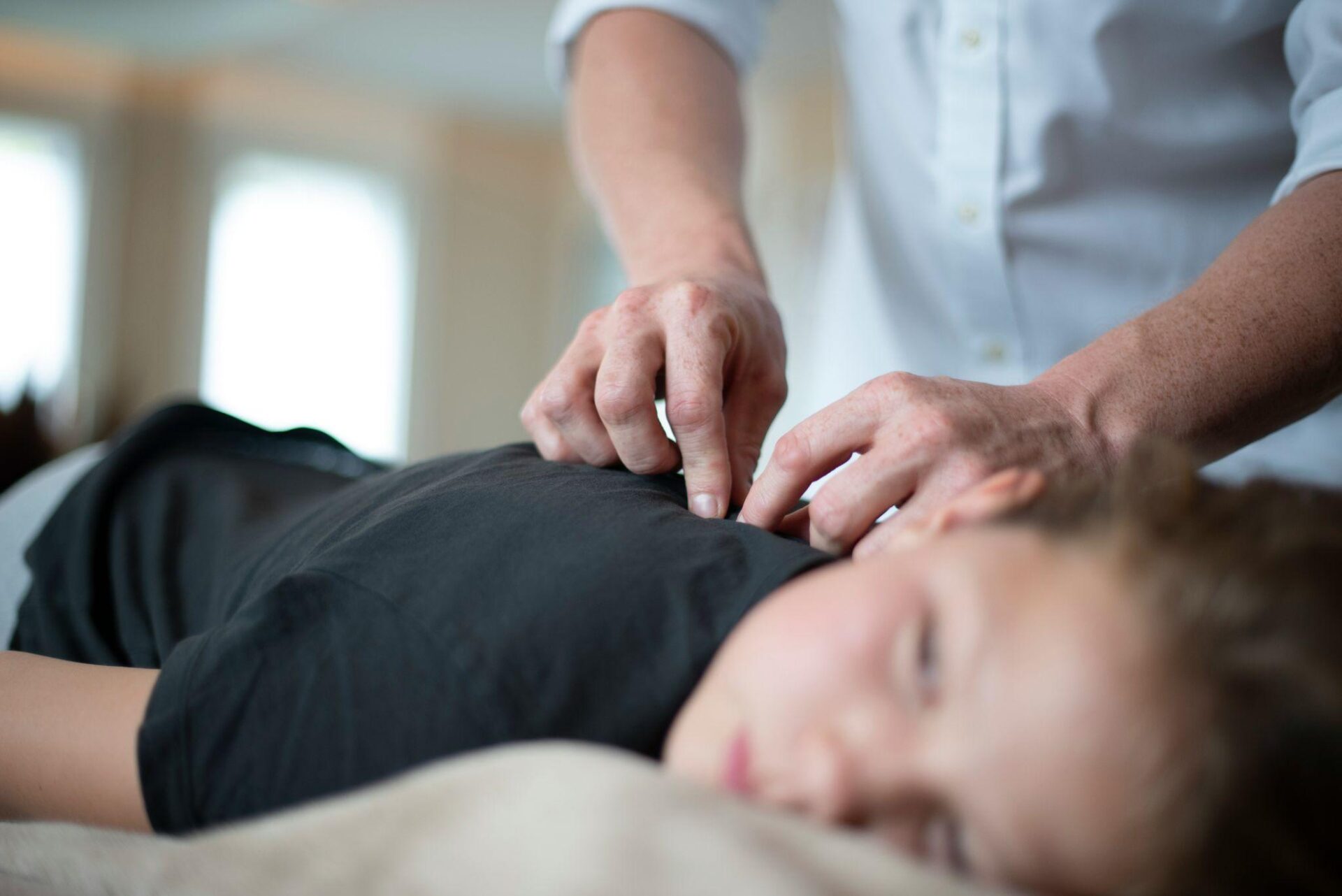 Quarterly Blog - Hands-On Health Care & Chiropractic - Hands-On Health Care & Chiropractic - How Clinical Massage Supports Chronic Pain Relief Beyond Relaxation - Image 2 Clinical massage therapist applying targeted pressure to a patient’s upper back during a treatment session for chronic pain relief.